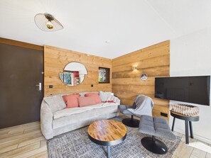 Un salon moderne comprenant un canapé, des fauteuils, une table basse et un téléviseur.