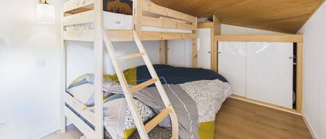A bunk bed room with a wooden ceiling and white walls.