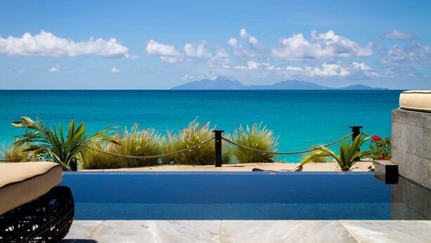 Une piscine à débordement offrant une vue sur l’océan et les montagnes.