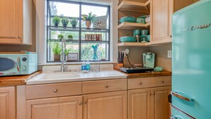 A kitchen with wooden cabinets, a window with plants, a vintage refrigerator, and a microwave. - Perfect Couples Getaway, Heated Pool Access (Tybee Island)