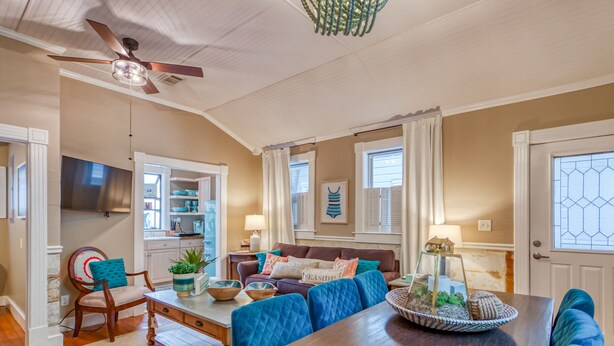 A spacious living room with a wooden dining table, blue upholstered chairs, and a ceiling fan. - Perfect Couples Getaway, Heated Pool Access (Tybee Island)