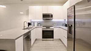 A modern kitchen with stainless steel appliances, white cabinetry, and a central island. - Amazing NEW 3 bedroom+loft townhouse in Hidden Forest, with private pool! (Clermont)