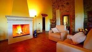 Una sala de estar acogedora con chimenea, paredes de piedra y asientos cómodos.
