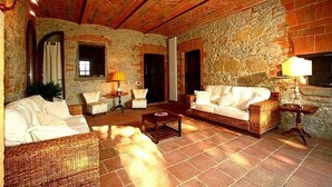 Una sala de estar acogedora con muebles de mimbre, paredes de piedra y piso de baldosas.