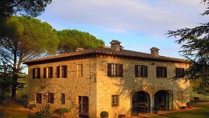 Un edificio de piedra con tejado de baldosas, varias ventanas y un porche cubierto.