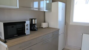 Eine kompakte Küche mit einer Brandt-Mikrowelle, einer Kaffeemaschine und einem Toaster.