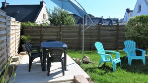 Eine Terrasse mit Tisch und Stühlen, einem blauen Sonnenschirm und einem Holzzaun.