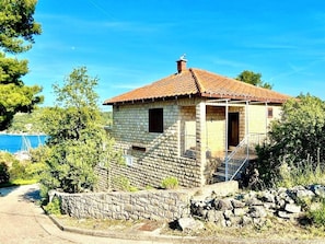 A stone house with a tiled roof, a porch, and a staircase leading to the entrance. -  Premium 2BR Sea-View Apartment with Huge 48m² Private Terrace – Rogač (Grohote)
