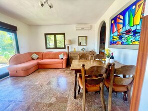 A living room with a sofa, dining table, chairs, and a colorful painting.