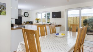Une cuisine moderne avec des meubles blancs, une cuisinière et un coin repas comprenant une table et des chaises.