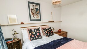 A neatly arranged bedroom with a bed, bedside tables, a lamp, and a framed artwork on the wall. - Sea Snug (Berwick-upon-Tweed)