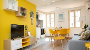 A bright yellow living room with a TV, sofa, and yellow chairs. There is a kitchen with a dining table and chairs. - Duplex with terrace - hyper-center of Toulon (Toulon)