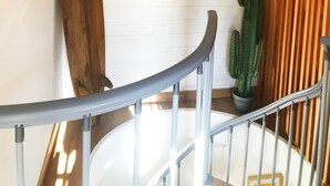 A staircase with a metal railing, a wooden surfboard leaning against the wall, a framed picture of a beach scene, and a cactus plant. - Duplex with terrace - hyper-center of Toulon (Toulon)