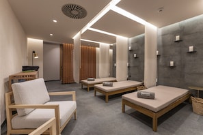 A modern spa room with wooden furniture, a massage table, and a wall-mounted massage chair. - Barceló Tenerife Royal Level (San Miguel de Abona)