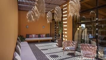 An outdoor seating area with a bench, wicker chairs, and a potted plant.