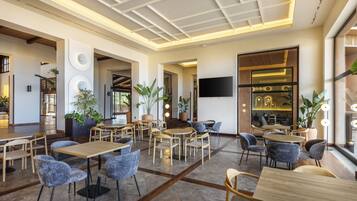 Un restaurante moderno con mesas y sillas de madera, plantas en macetas y un televisor de pantalla plana en la pared.