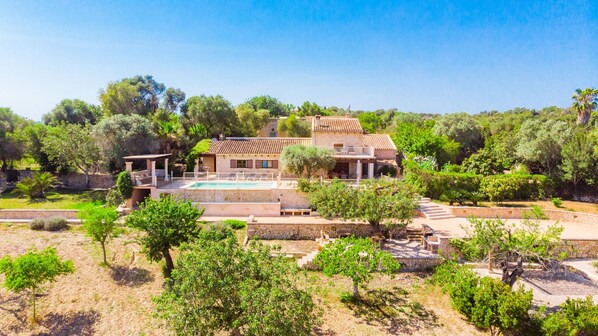 Une villa dotée d’une piscine, entourée d’une végétation luxuriante et de sentiers en pierre.