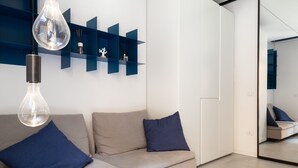 Un salon moderne avec un canapé beige, deux coussins bleus et un luminaire suspendu.