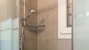 Un espace douche doté d’une porte en verre, d’un pommeau de douche et d’une étagère.