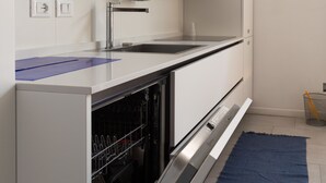 Une cuisine moderne avec des meubles blancs, un évier en acier inoxydable et un lave-vaisselle.