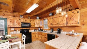 A wooden cabin-style kitchen with a tiled floor, wooden cabinets, a microwave, a coffee maker, and hanging light fixtures. - 1BR-hot tub-pool table-close to Dollywood (1 free ticket)! (Sevierville)