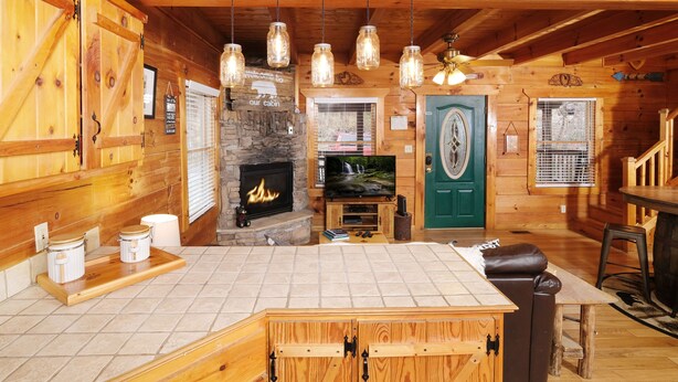A cabin interior with a fireplace, wooden walls, a green door, and a television. - 1BR-hot tub-pool table-close to Dollywood (1 free ticket)! (Sevierville)