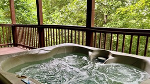 A hot tub with a wooden deck and a view of lush greenery. - 1BR-hot tub-pool table-close to Dollywood (1 free ticket)! (Sevierville)