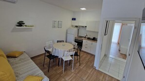 Un espacio habitable compacto con comedor, kitchenette y sofá.