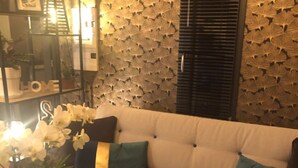 Un salon moderne avec un canapé d’angle, des coussins décoratifs et un mur orné d’un motif de feuilles.