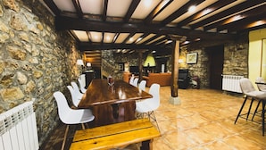 Un comedor rústico con pared de piedra, vigas de madera en el techo y piso de baldosas.