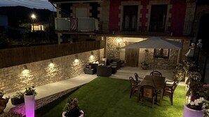 Un patio con zona de comedor, muros de piedra y plantas en macetas.