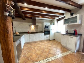 A kitchen with wooden beams, a tiled floor, and modern appliances. - La Casa del Pendo (Camargo)