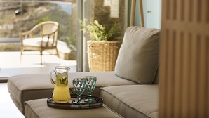 A modern living room with a sofa, a glass pitcher with a drink, and two glass cups on a tray. - The Suite by Heliades Villas – Idyllic Getaway in Andros, pool, 2-bedrooms (Cyclades)