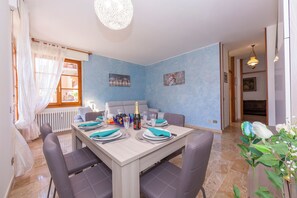 A dining area with a table set for four, a sofa, and a decorative plant.