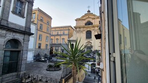 A courtyard with buildings, a palm tree, and a church with a bell tower.