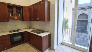 A kitchen with wooden cabinets, a gas stove, an oven, and a sink.
