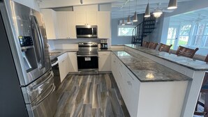 Una cucina moderna con elettrodomestici in acciaio inossidabile, mobili bianchi e una grande isola con posti a sedere.