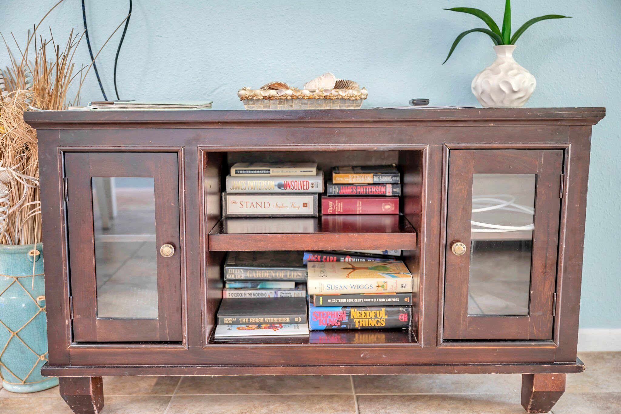 Un gabinete de madera con puertas de cristal y estantes llenos de libros.