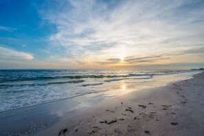 A beach with waves, a clear sky, and the sun setting or rising. - Updated Beachfront Condo, steps to John's Pass, heated pool,updated kitchen (Madeira Beach)