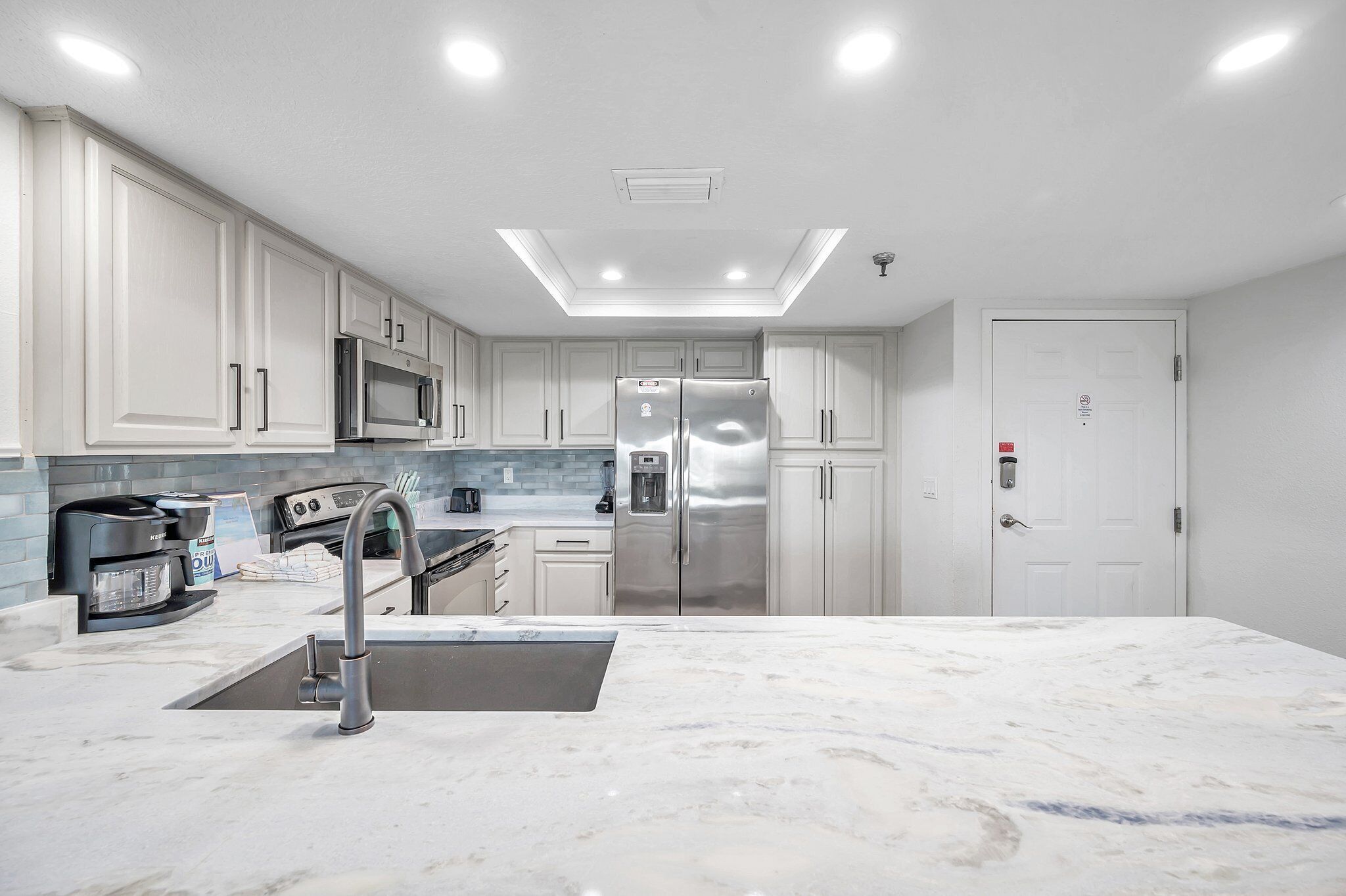 Una cocina moderna con armarios blancos, electrodomésticos de acero inoxidable y encimera de mármol.
