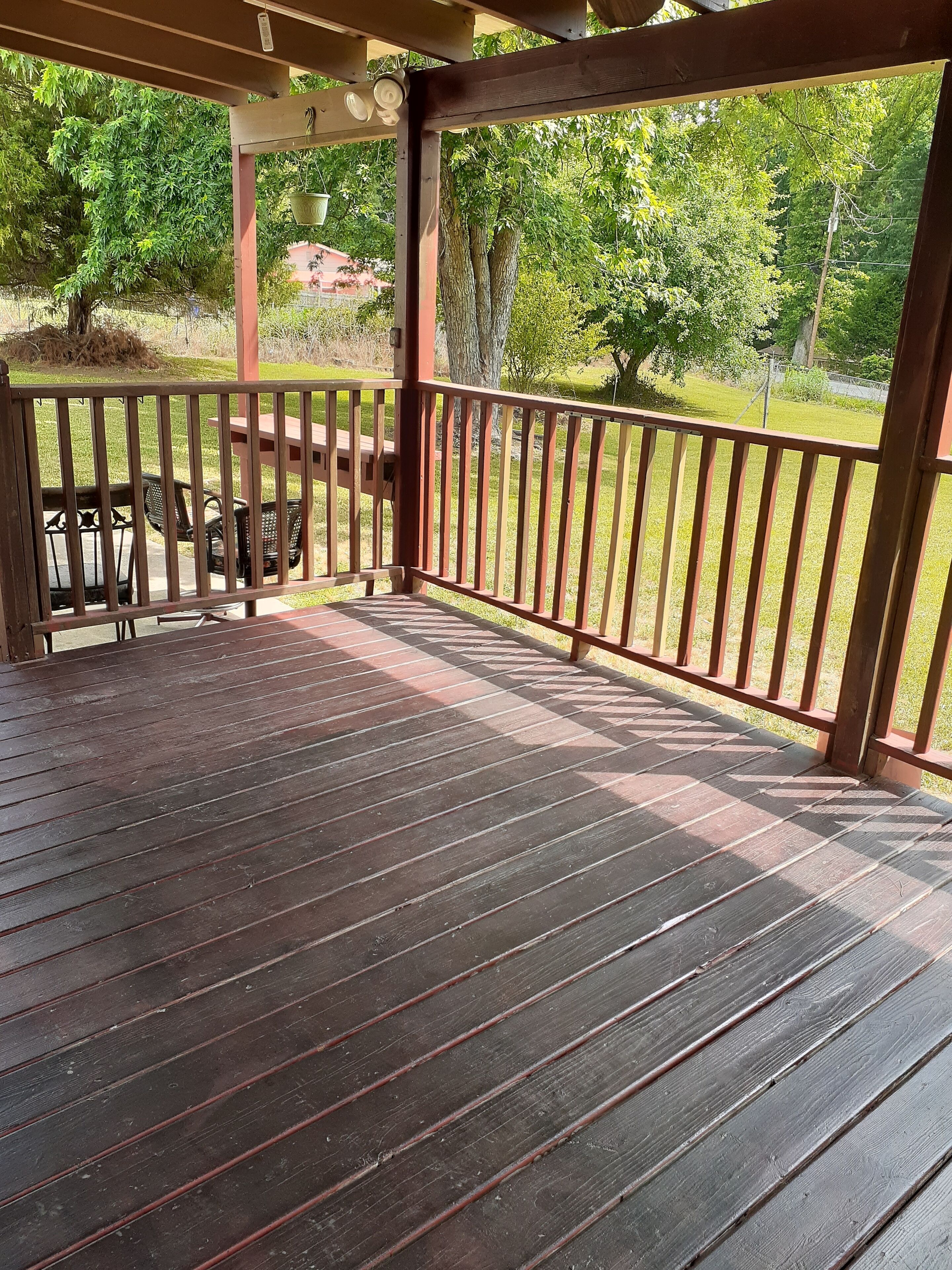 A wooden deck with a railing, a picnic table, and chairs.