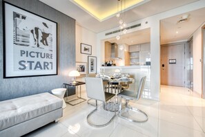 Ein modernes Wohnzimmer mit einer Couch, einem Esstisch für vier Personen und einem durch einen offenen Durchgang sichtbaren Küchenbereich.