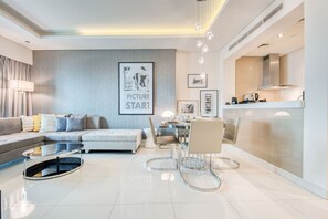 A modern living room with a sofa, coffee table, and dining area. There is a kitchen visible in the background. - Cool Dubai Apt next Burj Khalifa & Design District (Dubai)