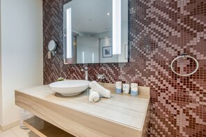 A modern bathroom with a large mirror, a sink, and a towel rack.