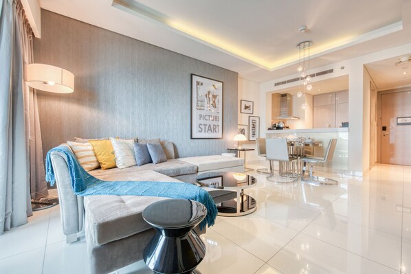 A modern living room with a sectional sofa, a coffee table, and a dining area with a round table and chairs.