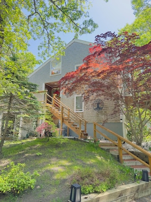 A two-story house with a wooden staircase leading to a balcony. - Cape Cod Villa pond front vacation home, retreat, spa, venue, film location (Harwich - Brewster Border)