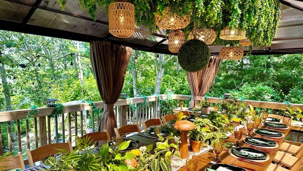 An outdoor dining area with wooden tables, chairs, and potted plants. - Cape Cod Villa pond front vacation home, retreat, spa, venue, film location (Harwich - Brewster Border)