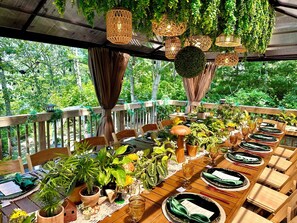 An outdoor dining area with wooden tables, chairs, and potted plants. - Cape Cod Villa pond front vacation home, retreat, spa, venue, film location (Harwich - Brewster Border)