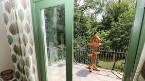 A view through a glass door with a wooden birdhouse and a metal fence in the background. - Trewrach Cottage (Newport)