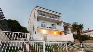 Un edificio residencial de varios pisos con balcones, entrada porticada y un césped bien cuidado.